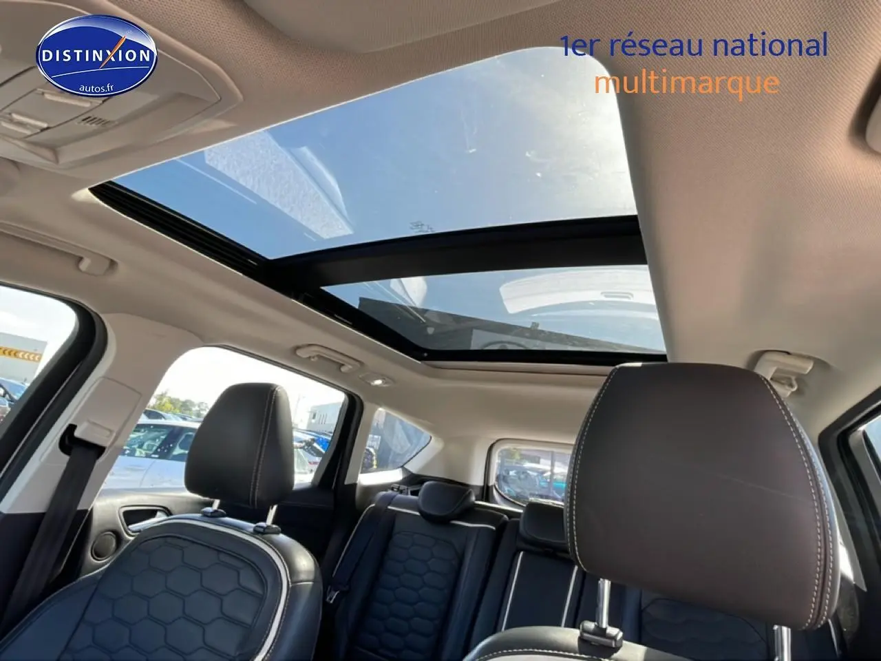Vue intérieure du Ford Kuga blanc 2017 montrant les sièges avant en cuir et le toit ouvrant panoramique en verre.