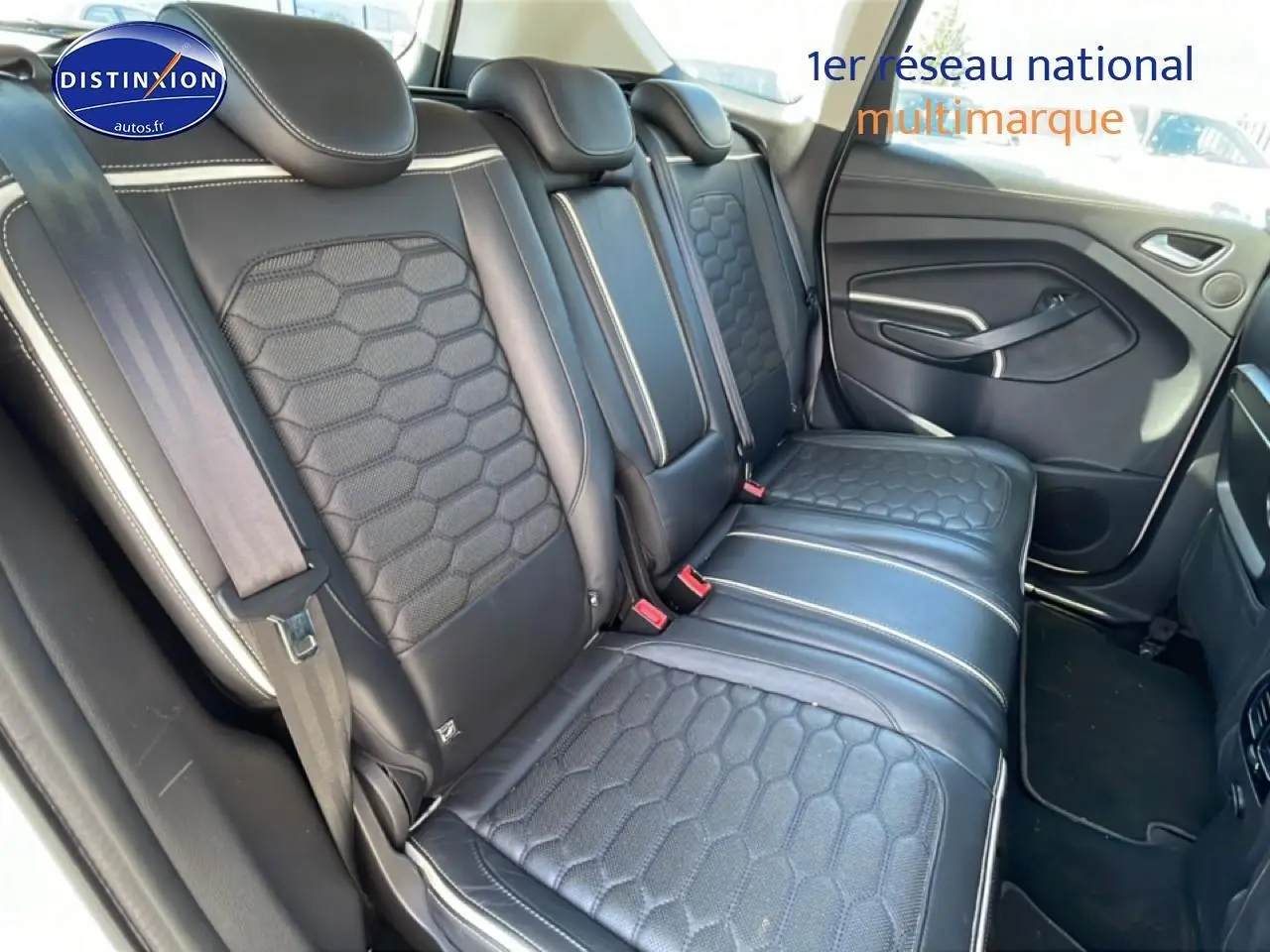 Vue intérieure en 3/4 arrière droit montrant la banquette arrière en cuir noir avec surpiqûres blanches du Ford Kuga blanc.