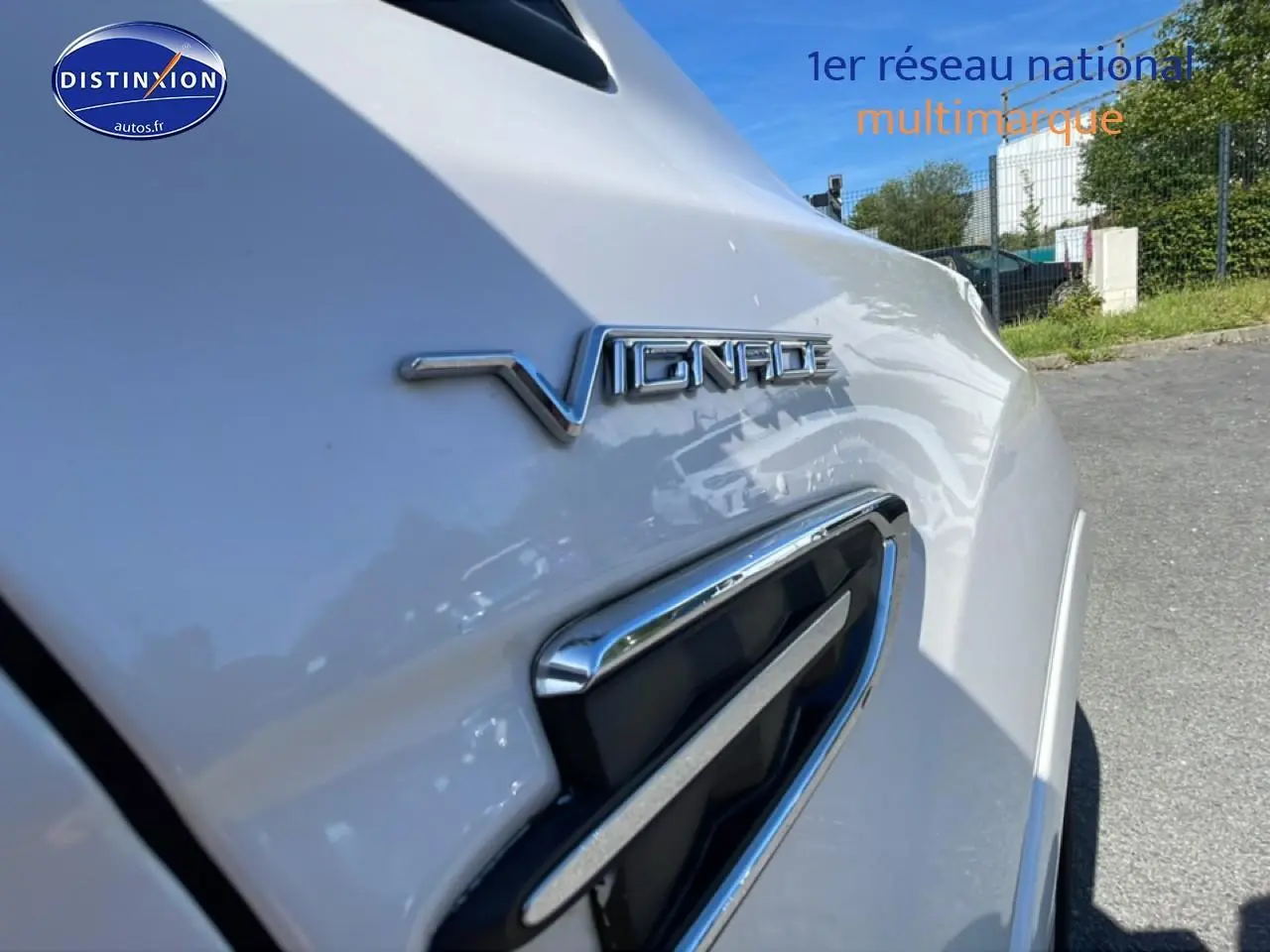 Gros plan sur l'aile avant droite blanche d'un Ford Kuga 2017 avec logo Vignale et prise d'air chromée.
