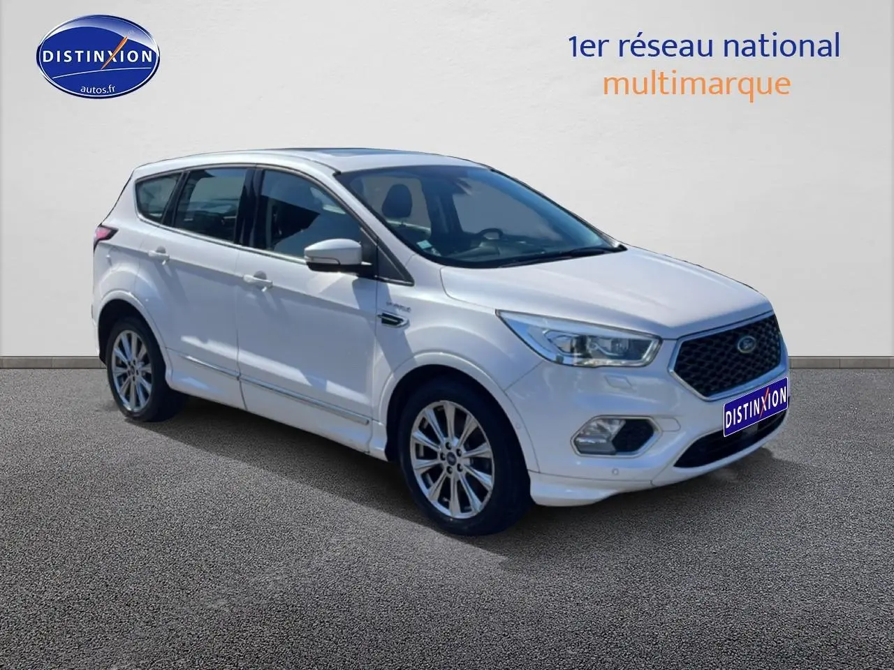 Vue 3/4 avant d'un Ford Kuga blanc 2017 avec jantes alu et calandre hexagonale distinctive.