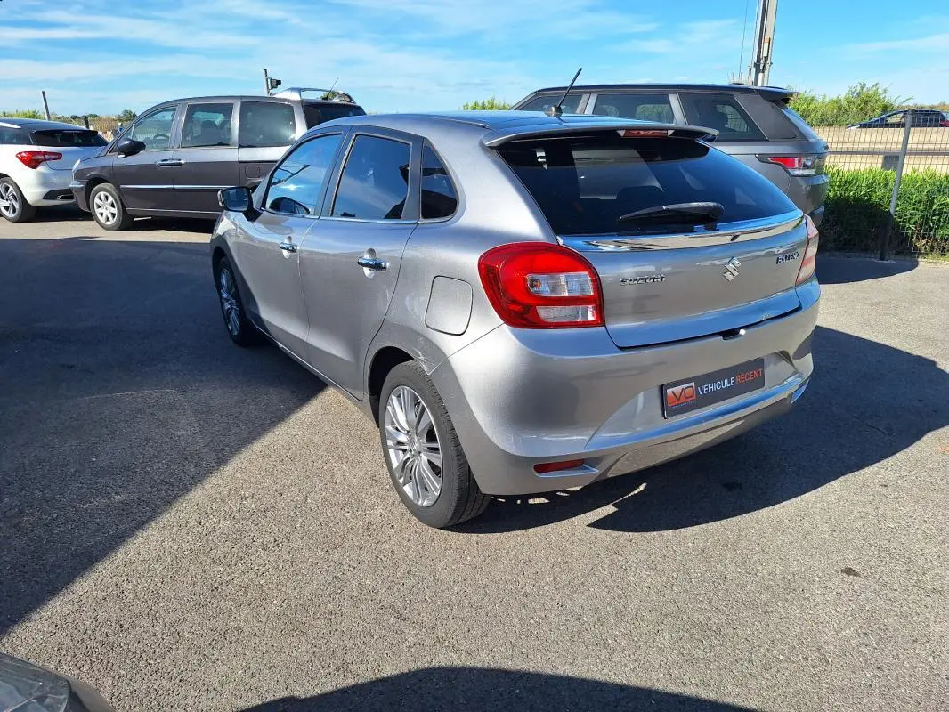 Vue 3/4 arrière droite d'une Suzuki Baleno gris clair avec vitres surteintées et jantes alliage 16 pouces.