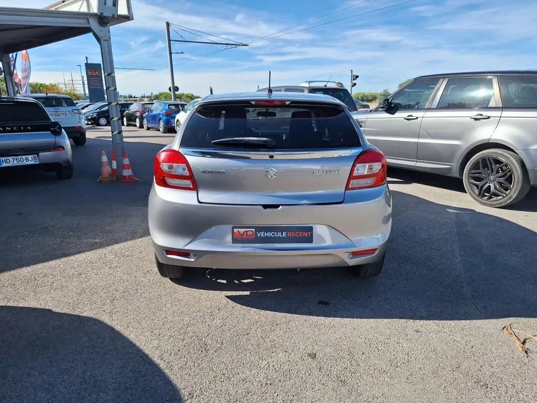 Vue arrière d'une Suzuki Baleno gris clair de 2017 avec vitres surteintées et jantes alliage 16 pouces.