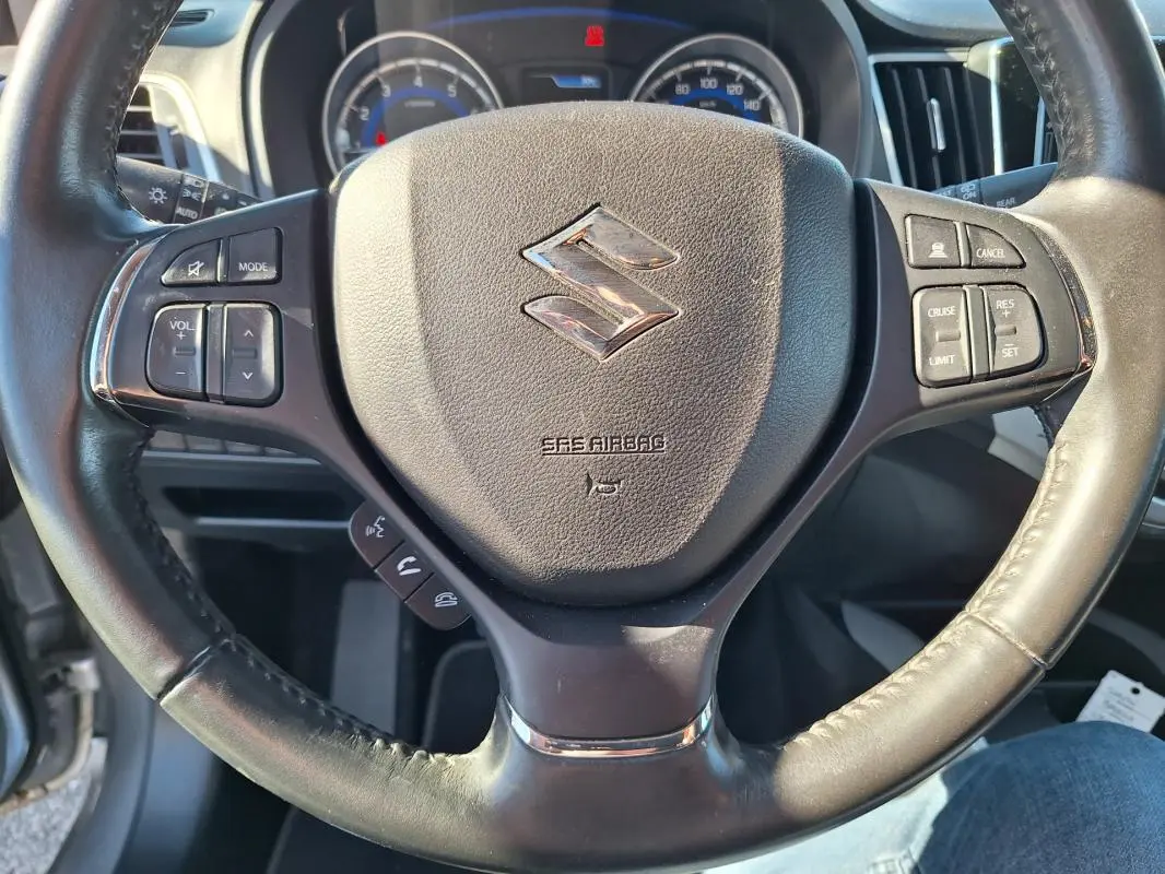 Gros plan sur le volant cuir noir de la Suzuki Baleno 1.0 Boosterjet Pack 2017 avec commandes intégrées.