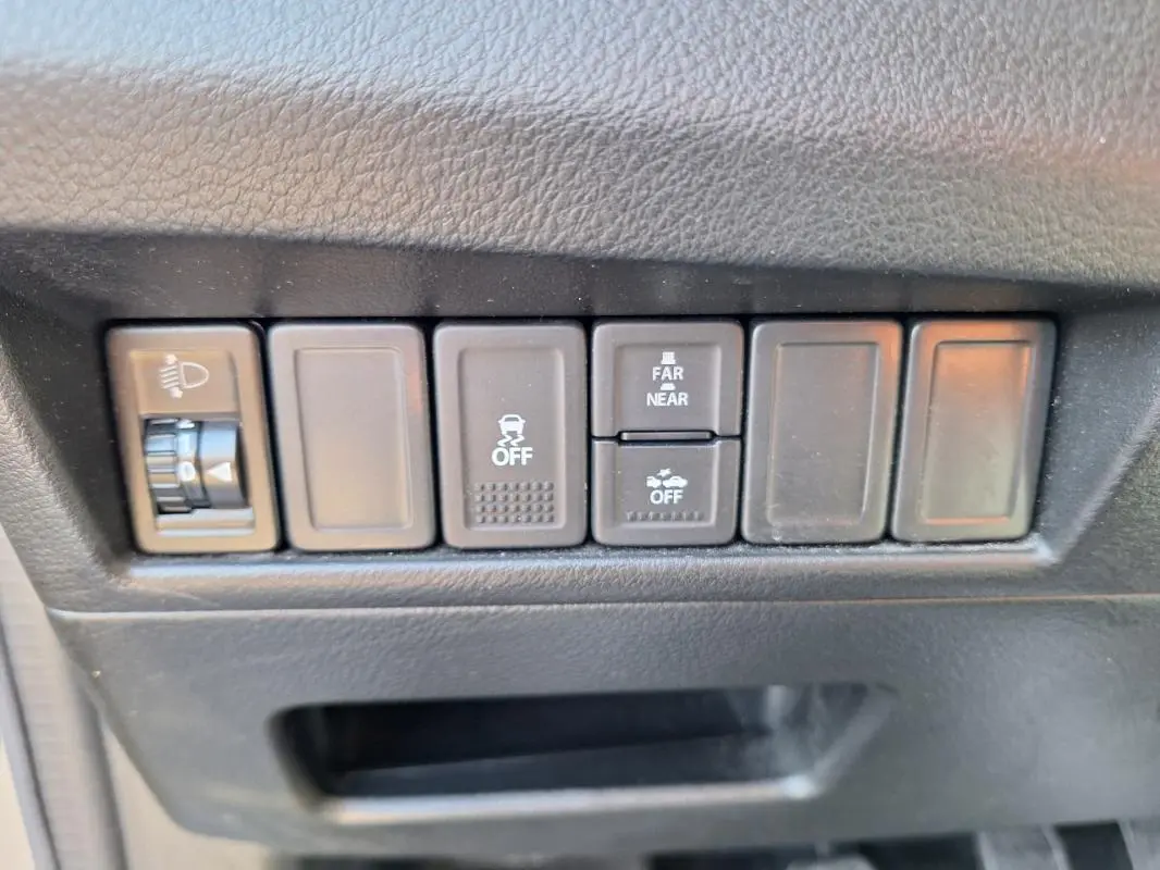 Gros plan sur les boutons de commande noirs du tableau de bord d’une Suzuki Baleno gris clair, version 2017.