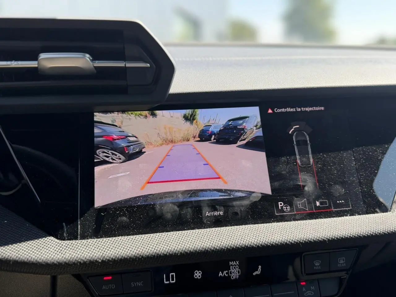 Écran de caméra de recul affichant l’arrière d’une Audi A3 Sportback noire avec guidage de trajectoire visible.