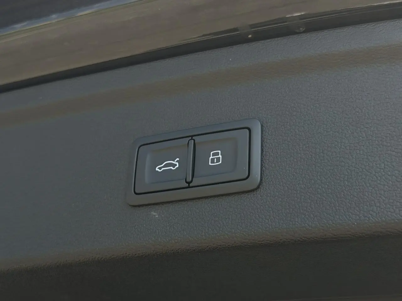 Boutons de commande du hayon assisté et verrouillage sur le coffre d'une Audi A3 Sportback noir Mythe 2025.