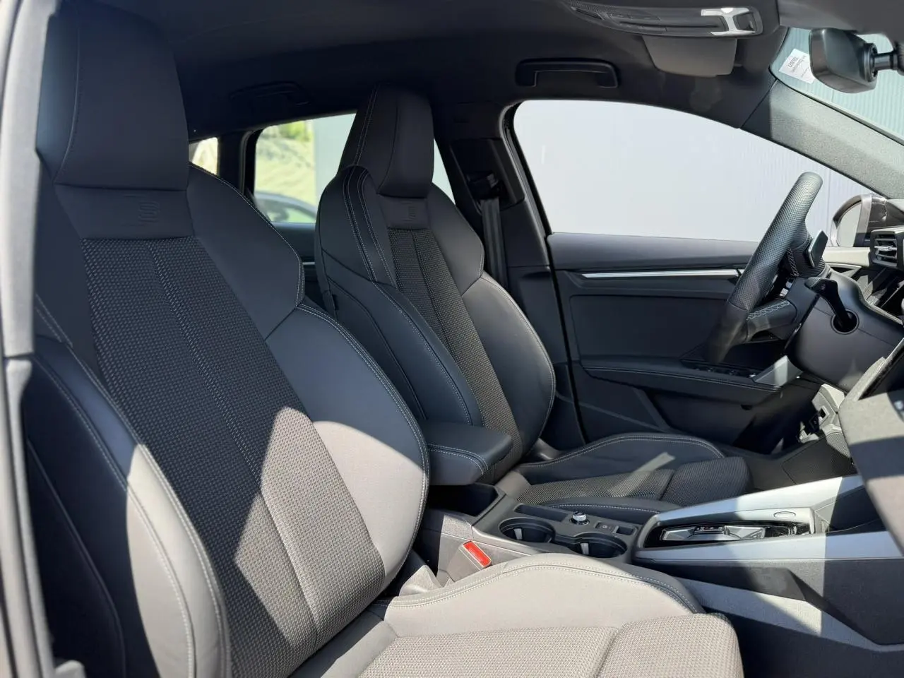 Vue intérieure côté droit de l’Audi A3 Sportback 2025 avec sièges sport noirs et console centrale moderne.