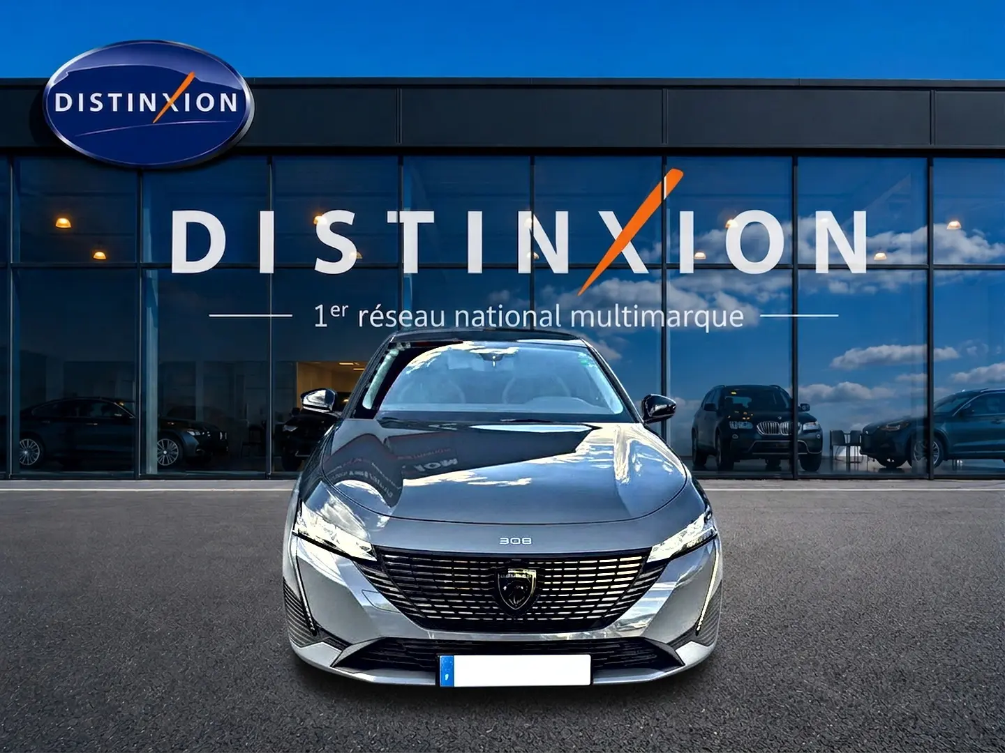 Vue avant d'une Peugeot 308 gris selenium garée devant une vitrine avec logo Distinxion.