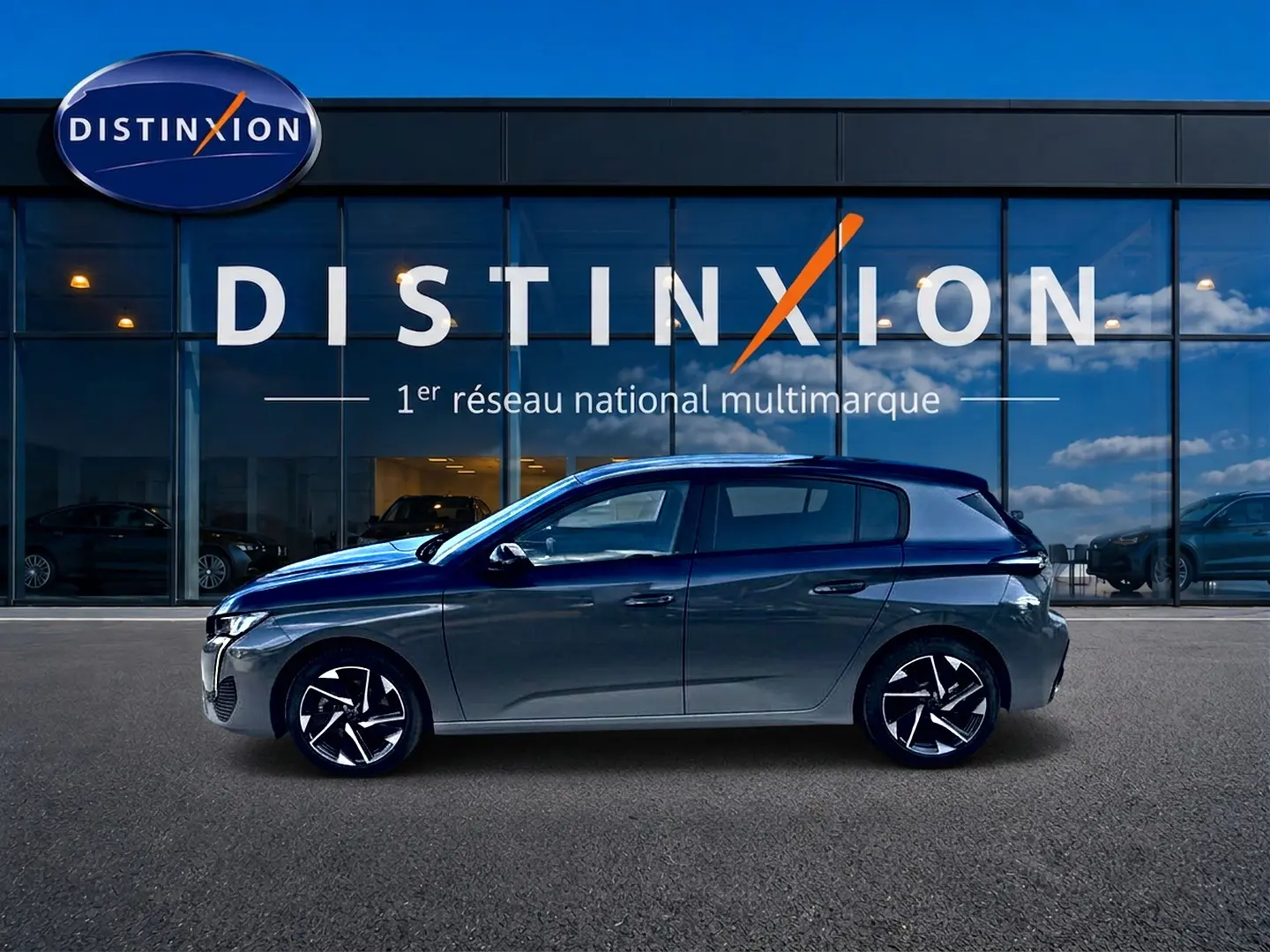 Peugeot 308 gris selenium vue de profil côté gauche, avec jantes alliage et silhouette compacte devant une vitrine.