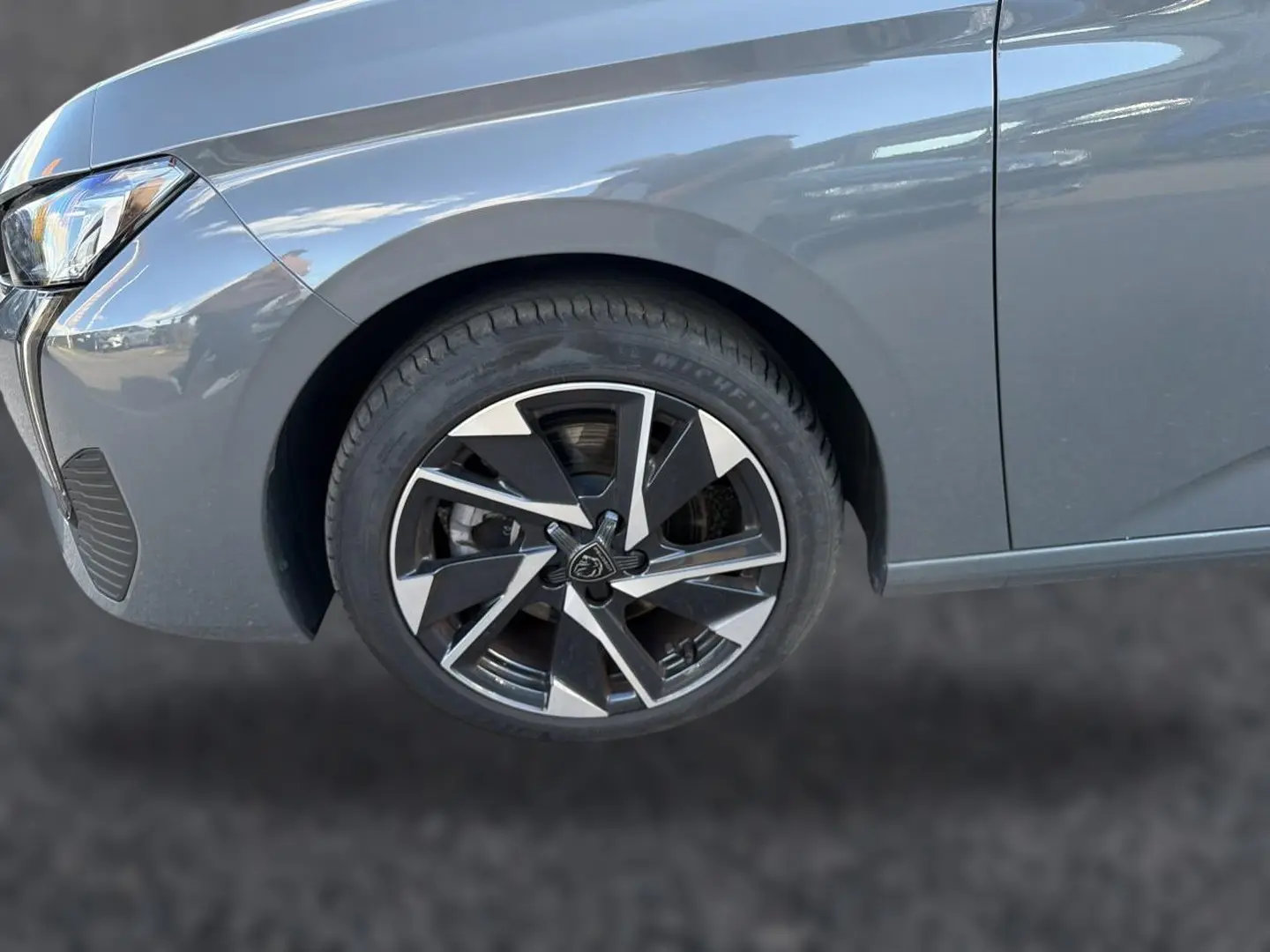 Gros plan sur la roue avant gauche et l'aile d'une Peugeot 308 gris selenium, mettant en valeur la jante alu design.
