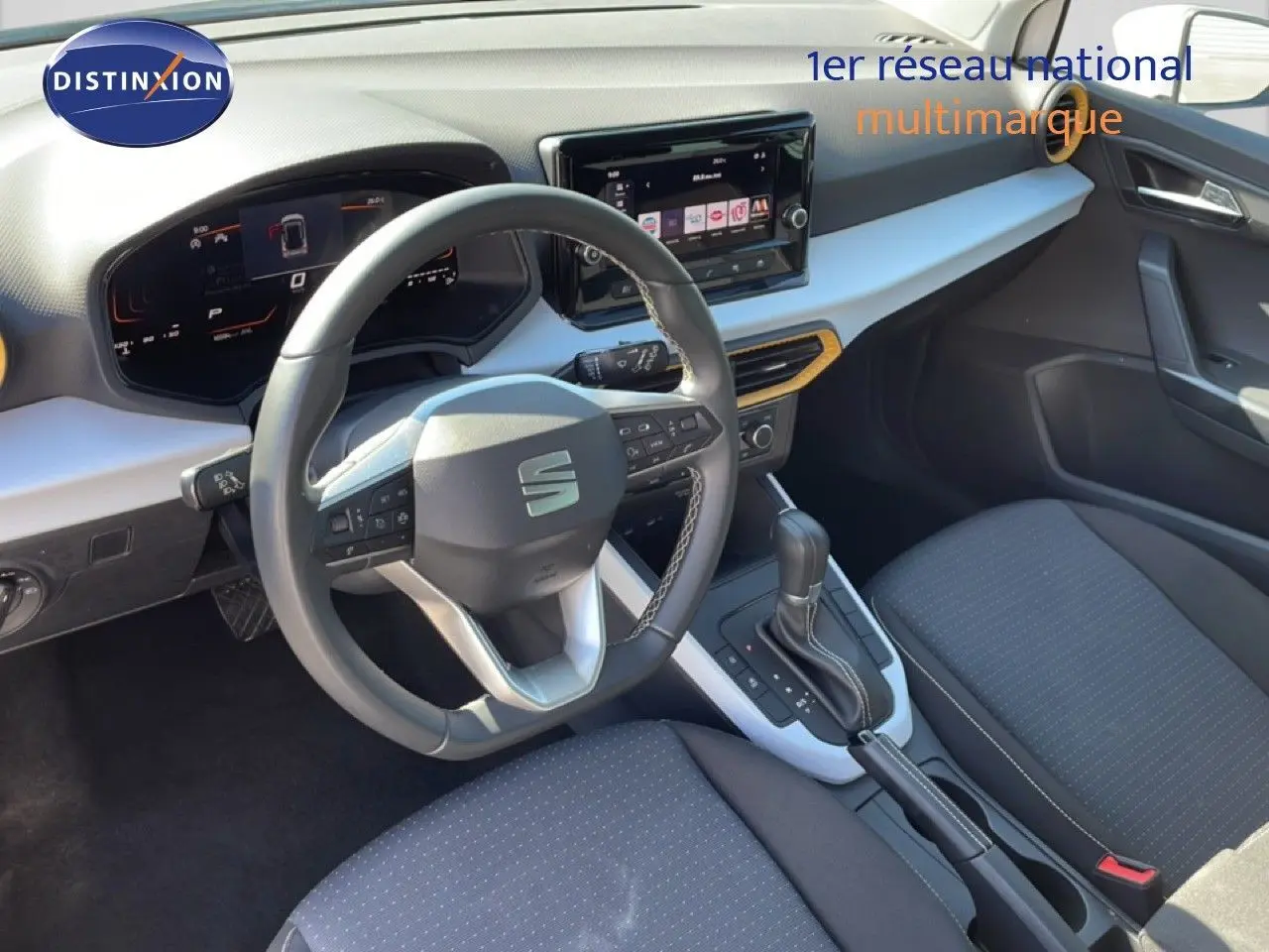 Vue intérieure côté conducteur du SEAT Arona blanc métal avec tableau de bord moderne et volant multifonction noir.