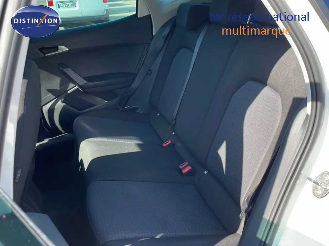 Vue intérieure des sièges arrière noirs d’un SEAT Arona blanc métal, avec ceinture de sécurité et porte arrière ouverte.