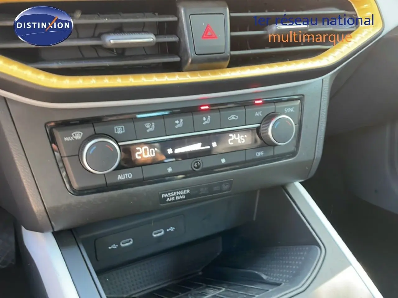 Gros plan sur la console centrale du SEAT Arona 2025, montrant la climatisation bi-zone avec éclairage LED jaune.