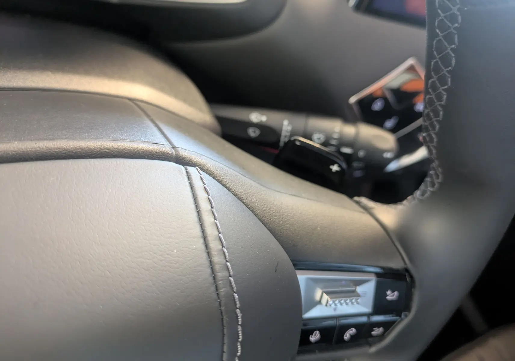 Gros plan sur le volant en cuir noir du DS3 2024 avec commandes intégrées et surpiqûres apparentes.