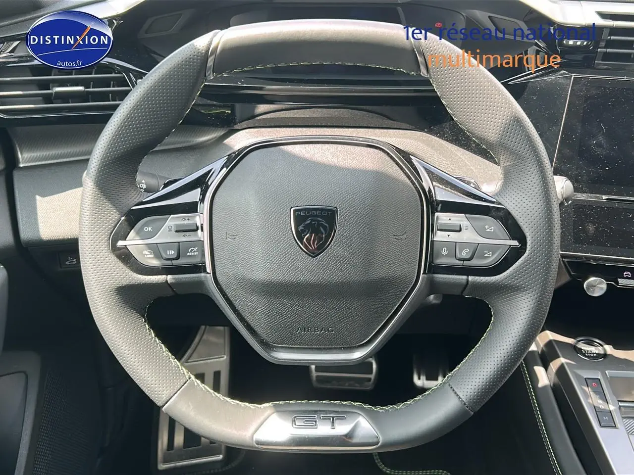 Vue rapprochée du volant cuir noir perforé avec logo Peugeot et badge GT du Peugeot 408 Hybrid 145 GT 2024.