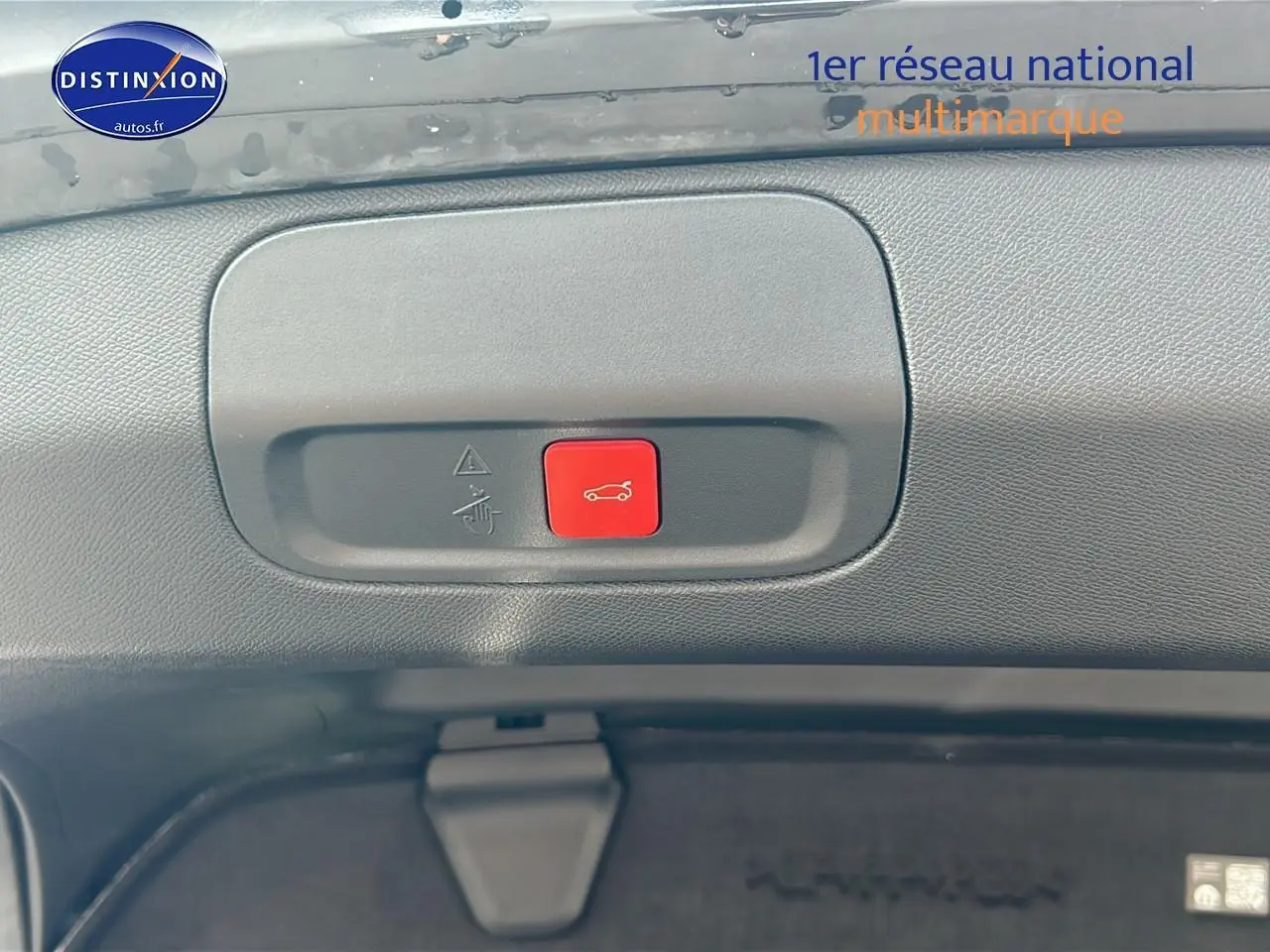 Gros plan sur le bouton rouge d'ouverture électrique du coffre du Peugeot 408 Hybrid 145 GT noir, vue intérieure arrière.