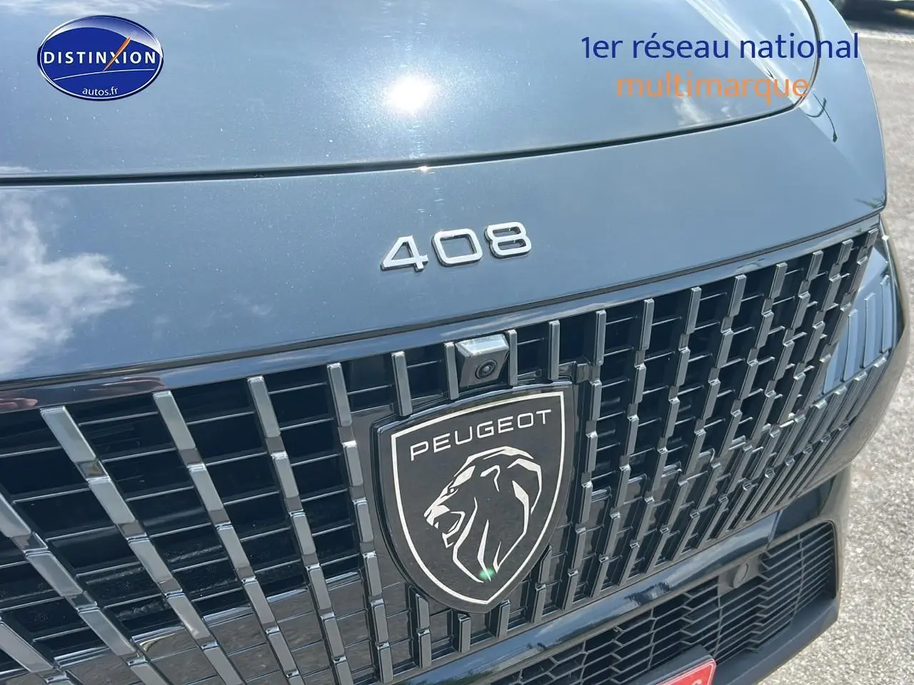 Gros plan sur la calandre noire brillante et le logo Peugeot du 408 Hybrid 145 GT e-dcs6 2024.