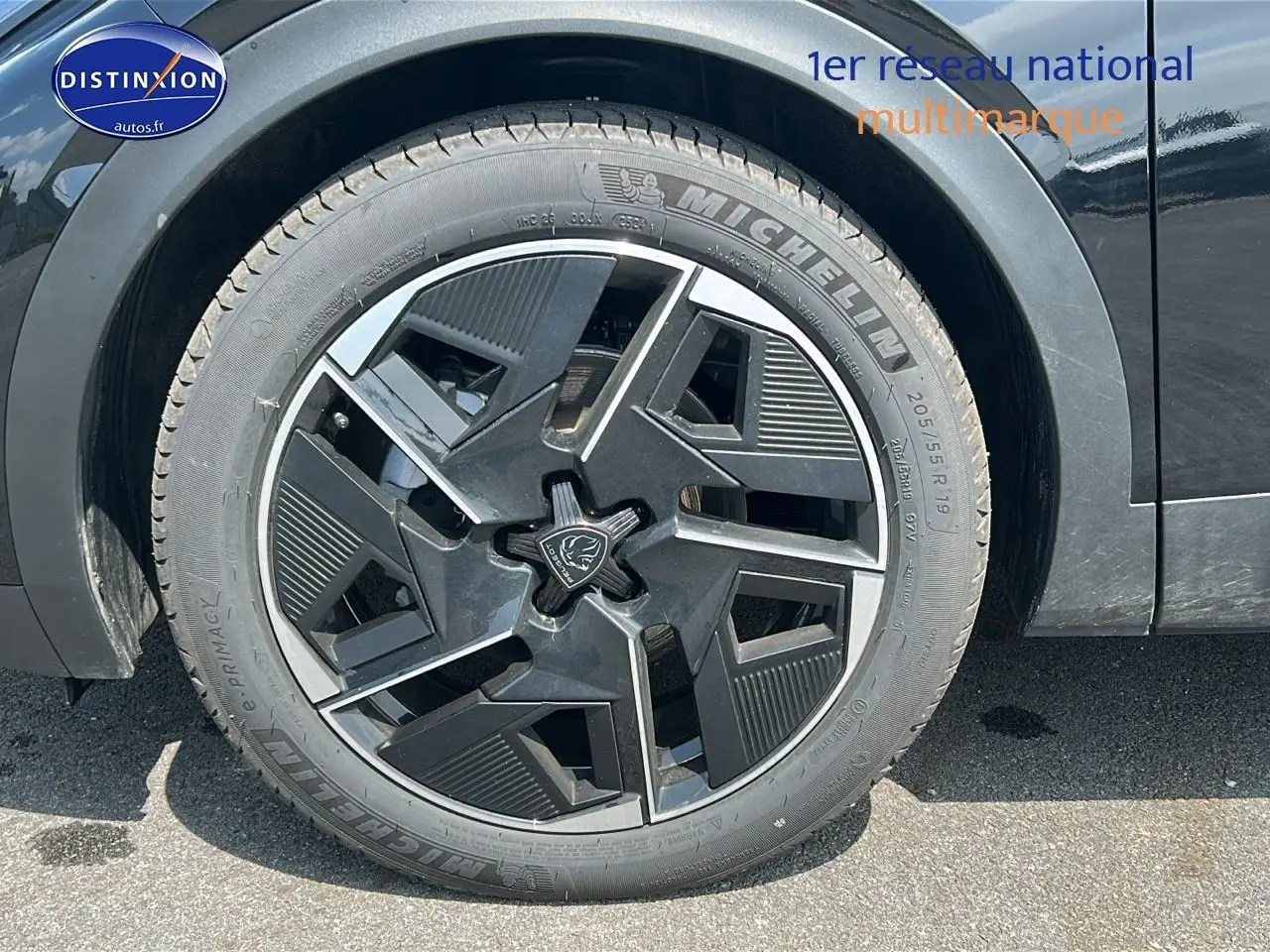 Gros plan sur la jante alu noire au design géométrique du côté avant gauche d'une Peugeot 408 Hybrid 145 GT noire.