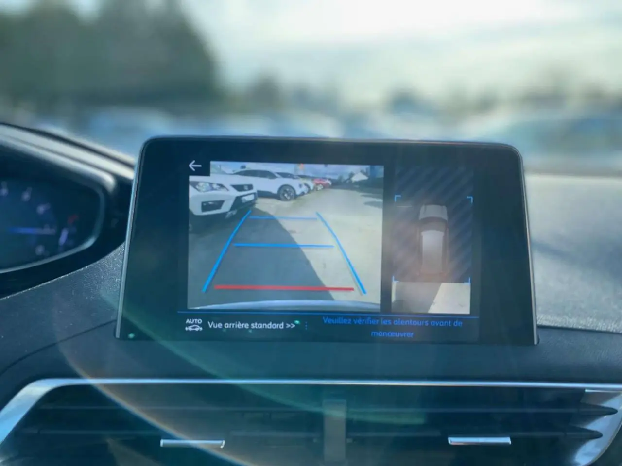 Écran tactile du Peugeot 3008 gris foncé montrant la caméra de recul avec vue arrière et vue de dessus du véhicule.