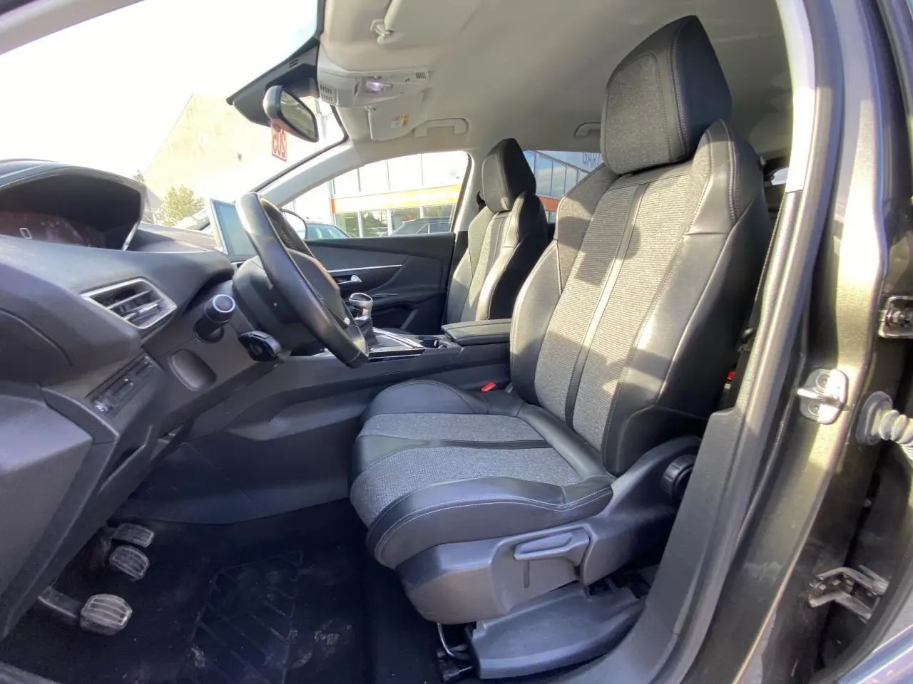 Vue intérieure côté conducteur du Peugeot 3008 gris foncé de 2019, montrant les sièges avant et le tableau de bord.