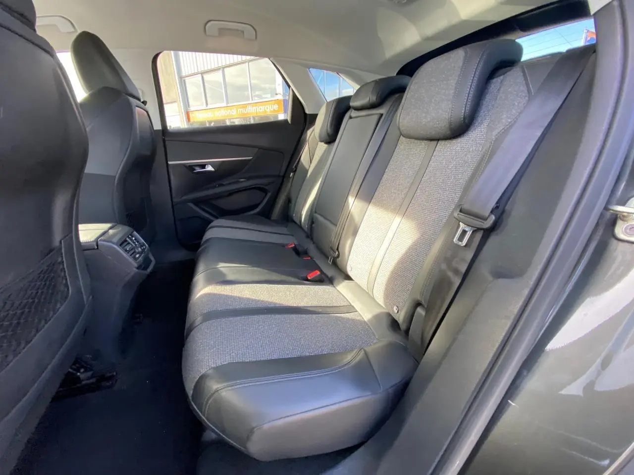 Vue intérieure arrière droite des sièges arrière en tissu et cuir du Peugeot 3008 gris foncé, avec ceinture de sécurité visible.