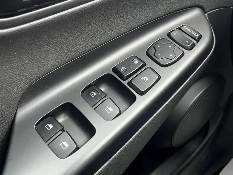 Gros plan sur les commandes de lève-vitres et rétroviseurs côté conducteur intérieur noir du Hyundai Kona bleu 2020.