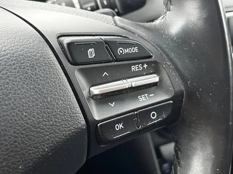 Gros plan sur les commandes de régulateur de vitesse au volant cuir noir d'une Hyundai Kona bleu 2020.