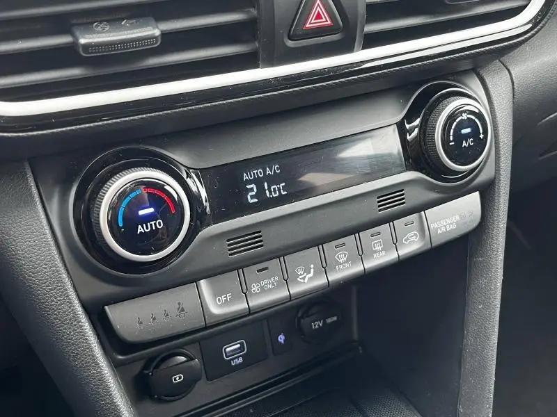 Vue rapprochée de la console centrale noire du Hyundai Kona 2020, affichant la climatisation automatique à 21°C.