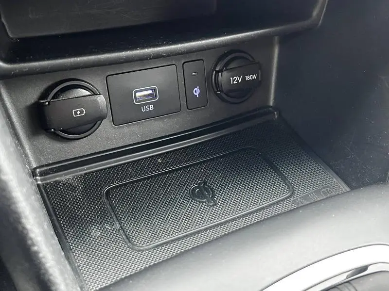 Gros plan sur la console centrale noire du Hyundai Kona 2020 avec prise USB, prise 12V, chargeur sans fil et prise accessoire.