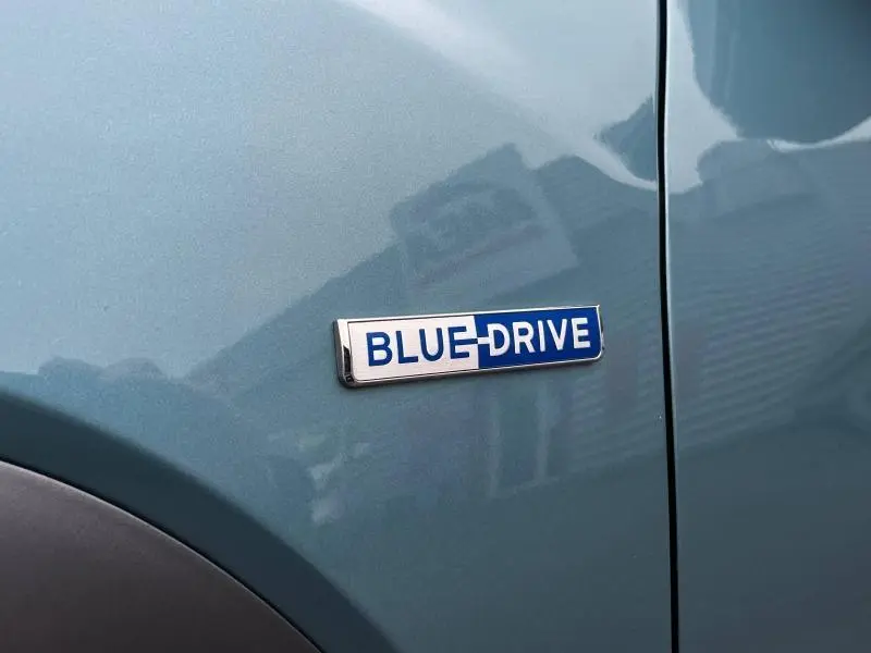 Gros plan sur l'écusson Blue Drive sur la carrosserie bleu céramique d'un Hyundai Kona hybride.