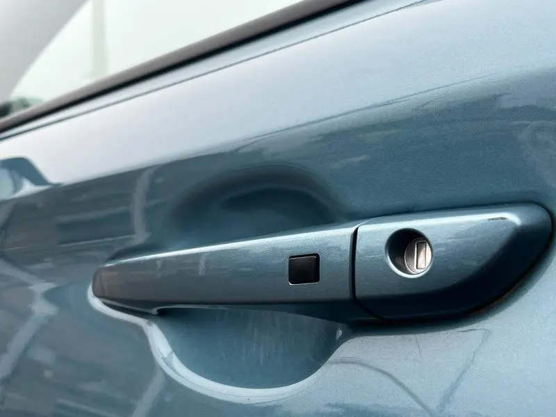 Poignée de porte bleue métallisée côté gauche de la Hyundai Kona hybride 2020 avec serrure et bouton de déverrouillage.