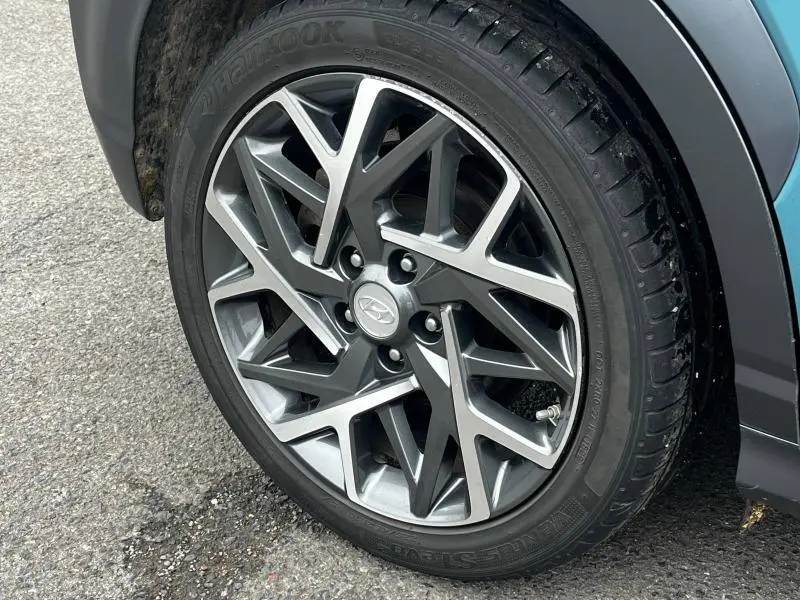 Gros plan sur la jante alu grise et noire du côté avant droit d’un Hyundai Kona bleu 2020 hybride.