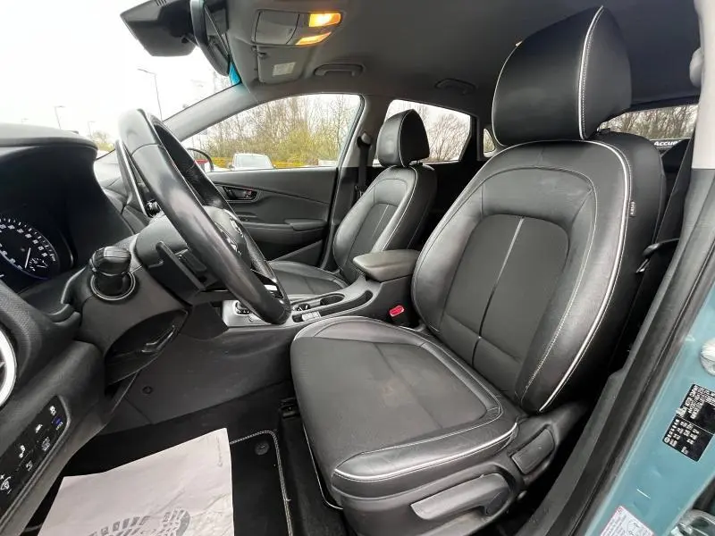 Vue intérieure côté conducteur du Hyundai Kona bleu 2020, sièges avant en cuir noir avec surpiqûres blanches.