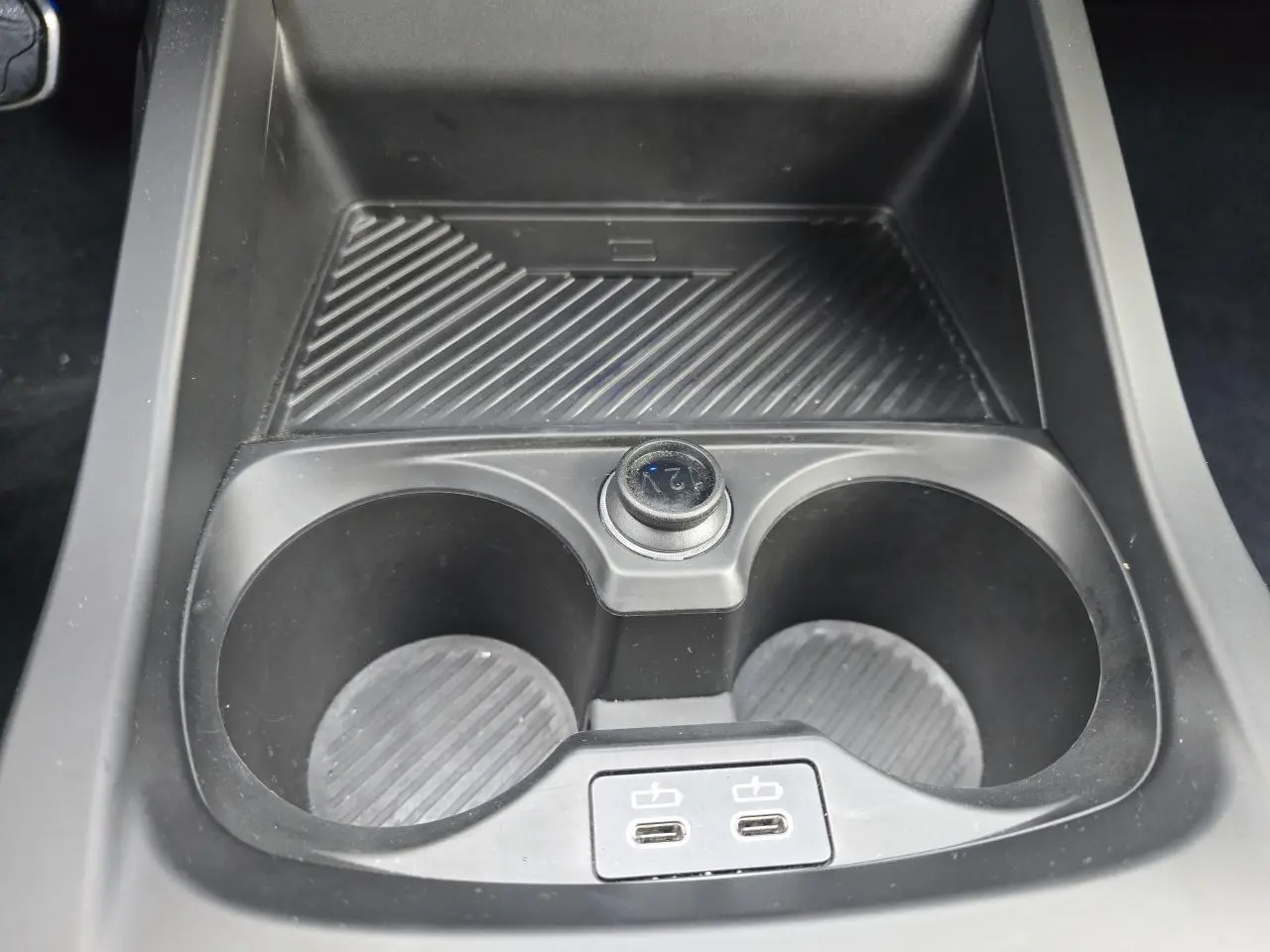 Gros plan sur la console centrale noire de la BMW Série 1 F70 avec porte-gobelets et deux ports USB-C.