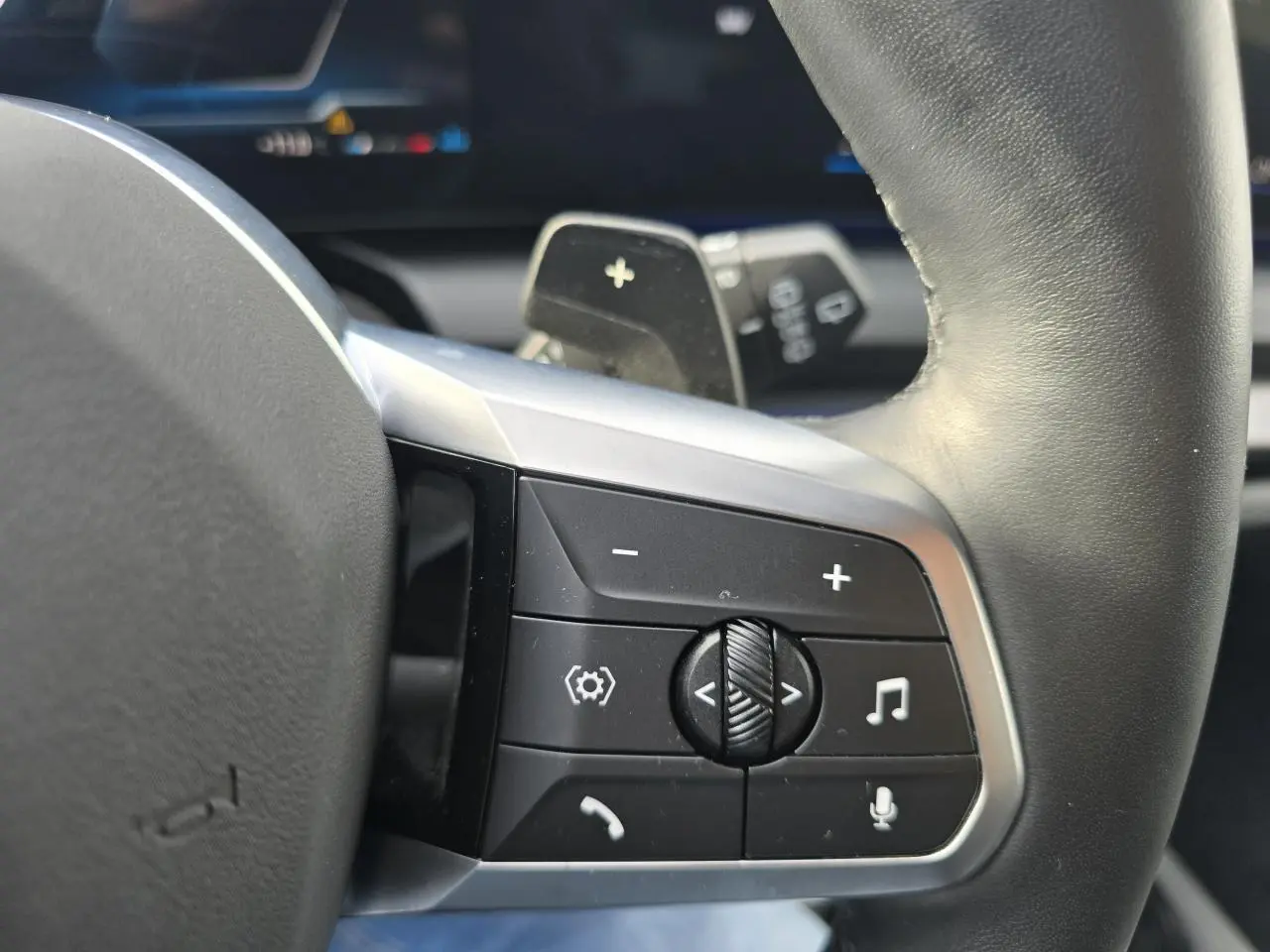 Gros plan sur les commandes au volant cuir noir de la BMW Série 1 F70 120 M Sport avec finition argentée.