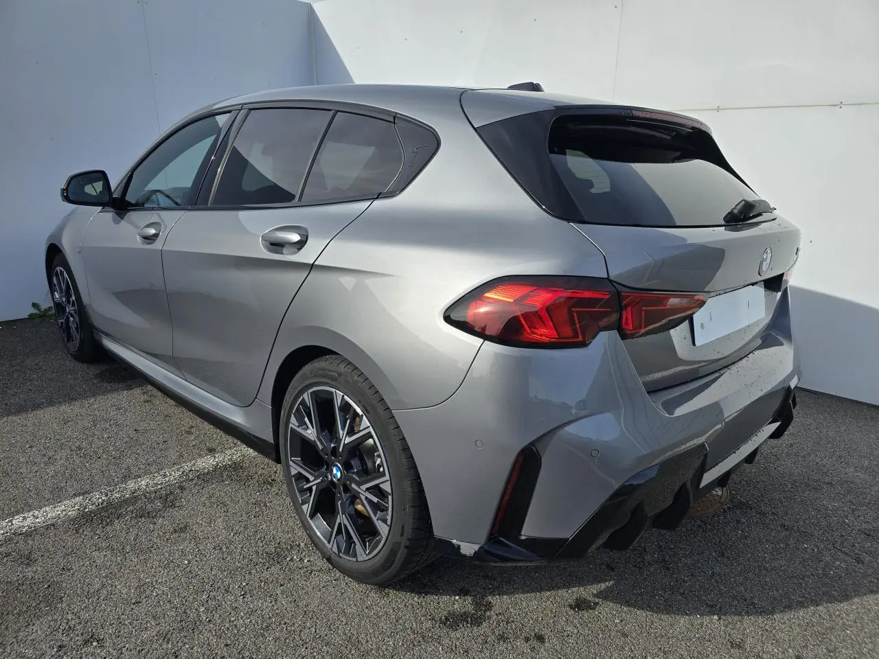 BMW Série 1 gris Skyscraper vue 3/4 arrière droit avec toit noir et jantes alliage 18 pouces M Sport.