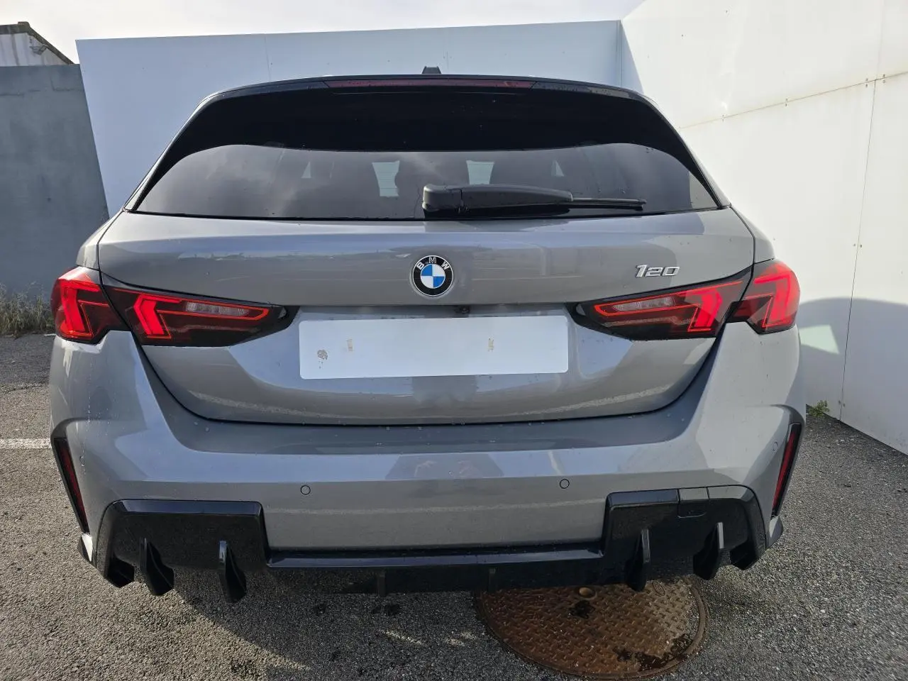 Vue arrière d'une BMW Série 1 120 M Sport gris Skyscraper avec toit noir et feux arrière LED allumés.