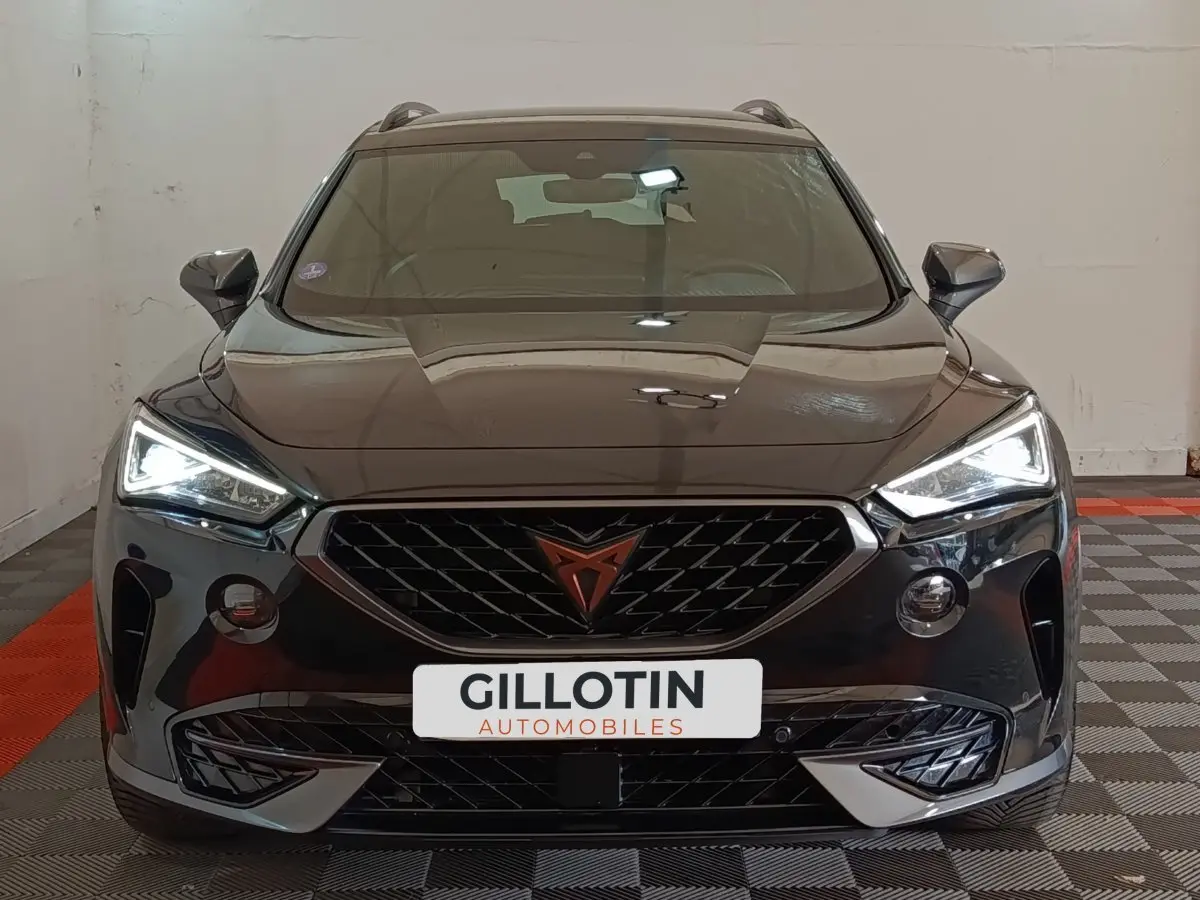 Vue frontale d'un CUPRA Formentor noir 2024 avec feux LED allumés et calandre distinctive au logo cuivré.