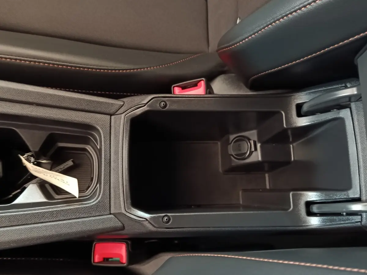 Vue plongeante sur le rangement central noir avec prise 12V et coutures orange du CUPRA Formentor 1.4 e-HYBRID 2024.