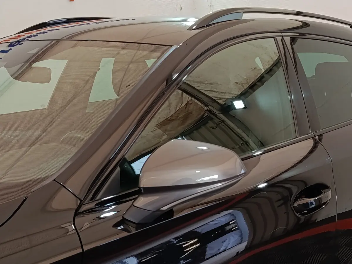 Vue rapprochée du côté gauche noir brillant du CUPRA Formentor 1.4 e-HYBRID avec rétroviseur ton caisse et rails de toit.