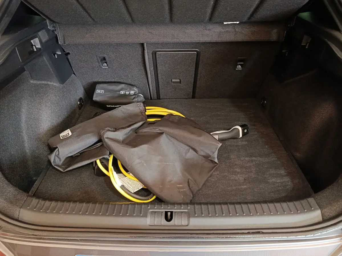 Coffre ouvert d’une CUPRA Formentor noir 2024, montrant le câble de charge hybride rangé au sol.
