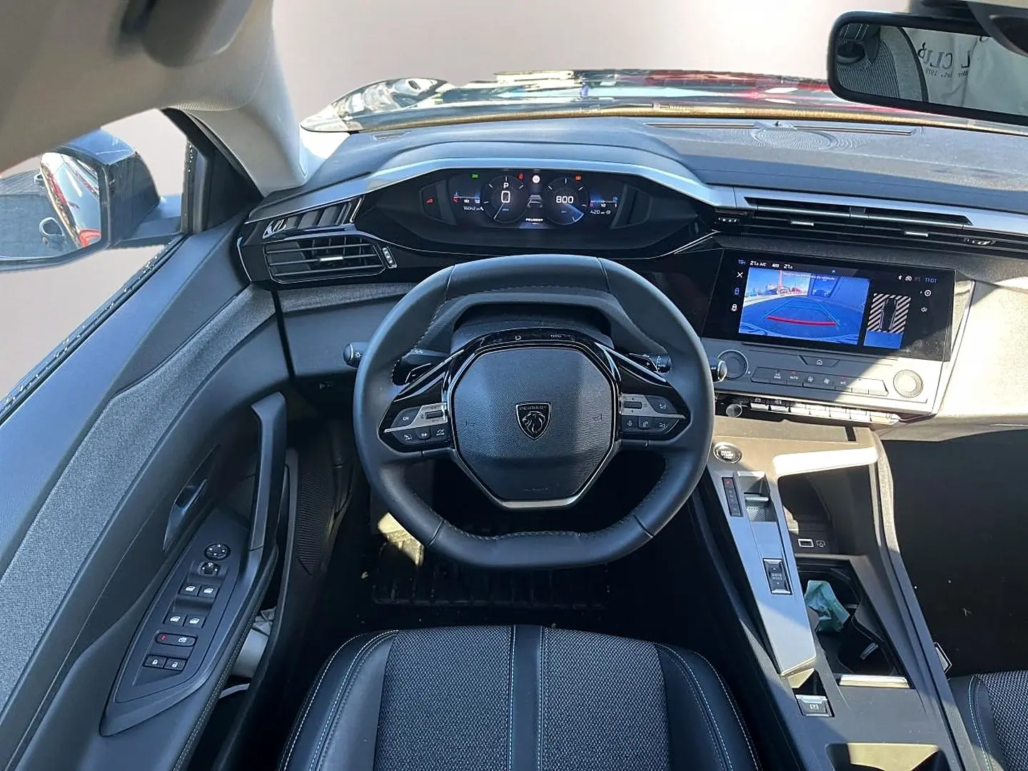 Vue intérieure frontale du poste de conduite noir de la Peugeot 308 1.5 BlueHDi avec écran tactile affichant la caméra de recul.