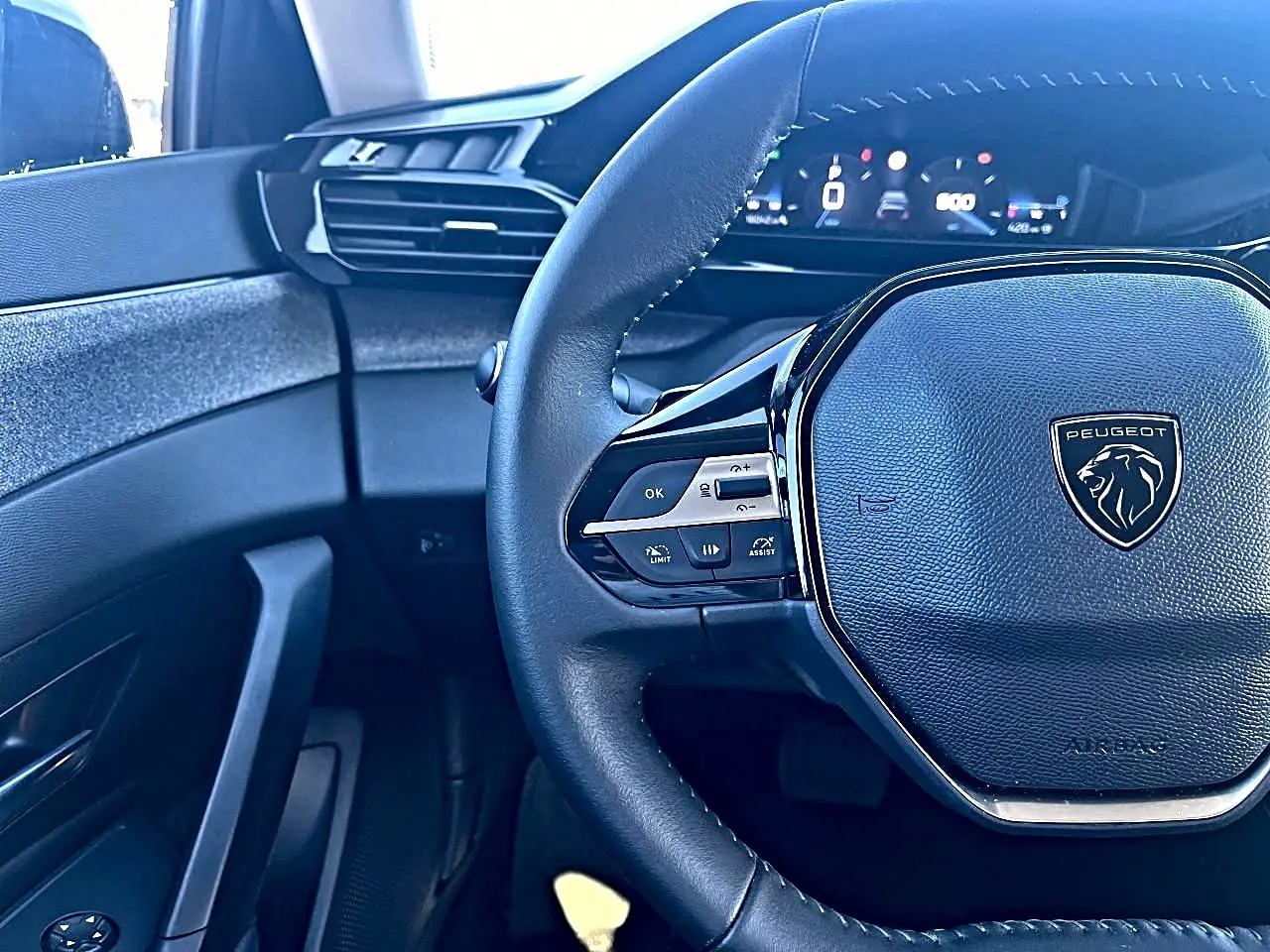 Vue rapprochée du volant noir multifonction et du tableau de bord numérique de la Peugeot 308 2025 côté conducteur.