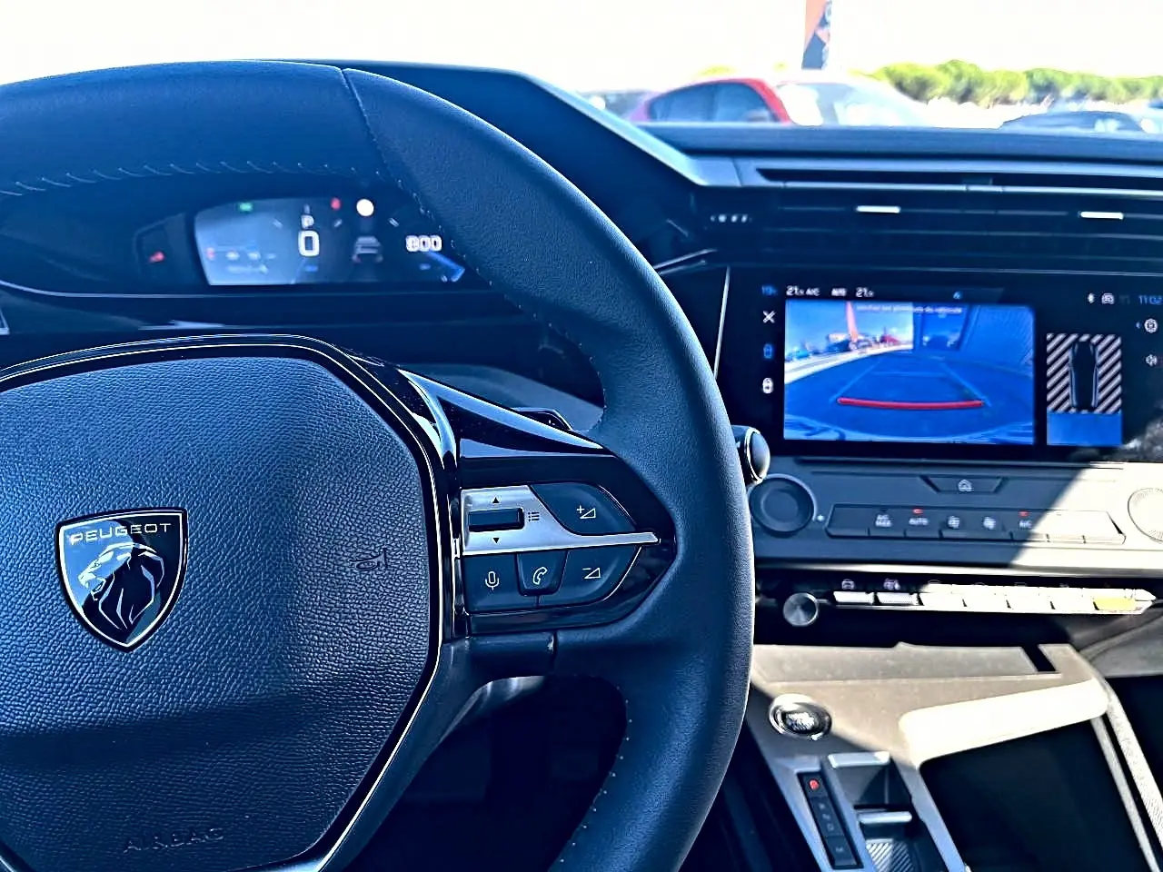 Vue intérieure centrée sur le volant noir Peugeot et l'écran tactile affichant la caméra de recul de la 308 2025.