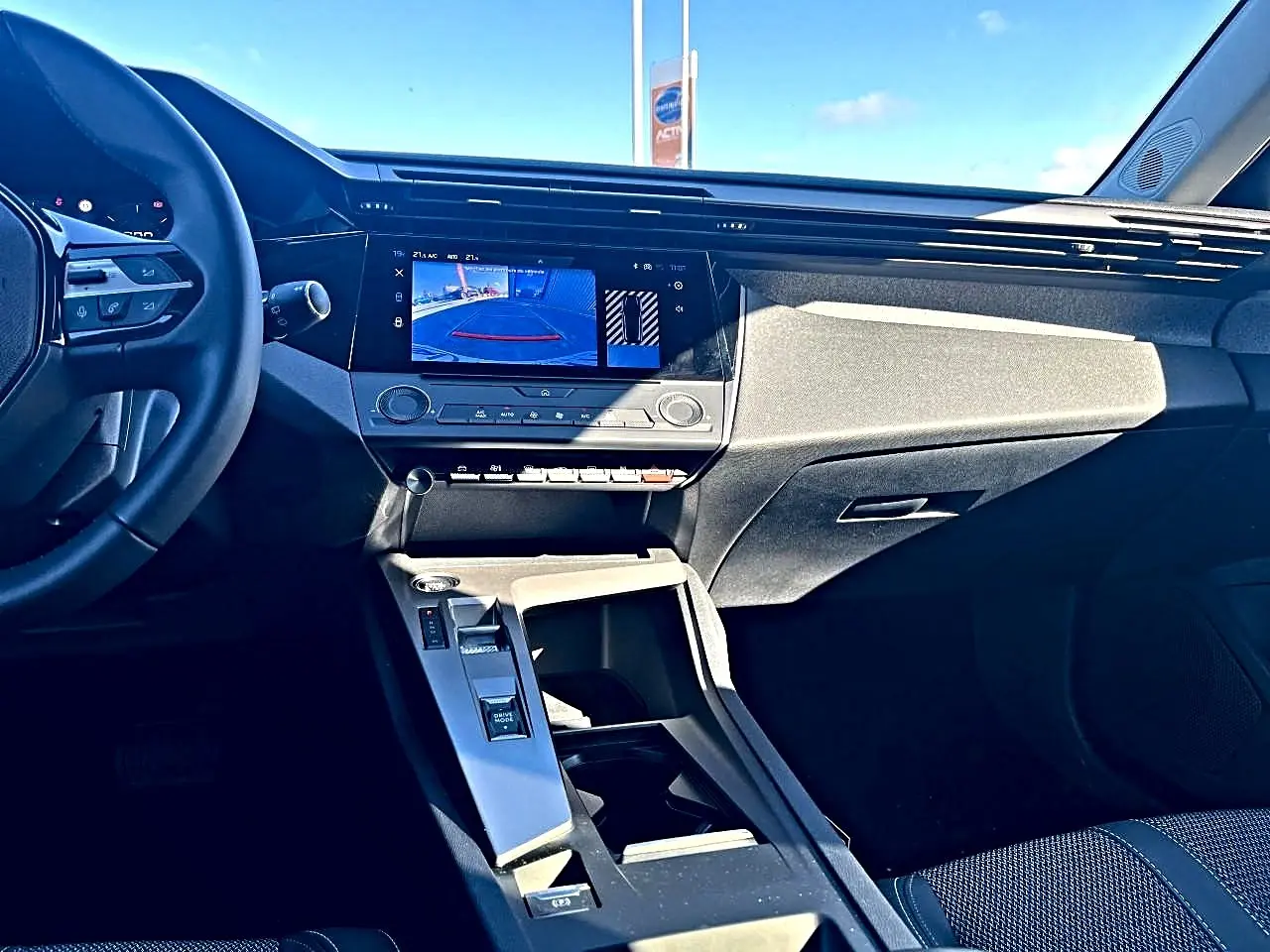 Vue intérieure avant droite de la Peugeot 308 noire, écran tactile affichant la caméra de recul et console centrale moderne.