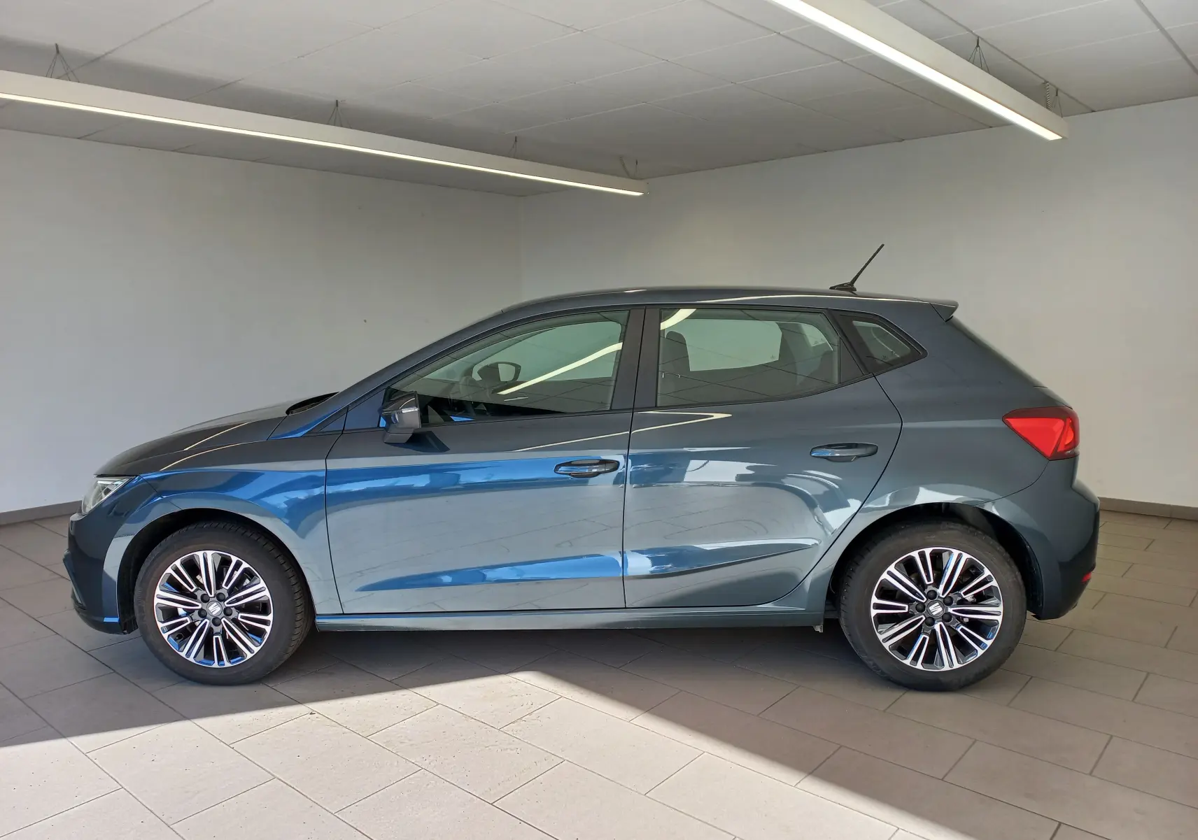 Vue de profil côté gauche d'une SEAT Ibiza 2025 gris magnétique, avec jantes alliage et antenne de toit visible.