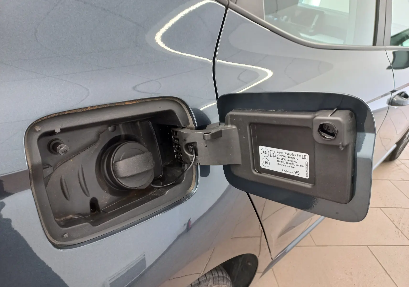 Gros plan sur la trappe à carburant ouverte côté gauche d’une SEAT IBIZA 2025 gris magnétique, essence E5/E10.