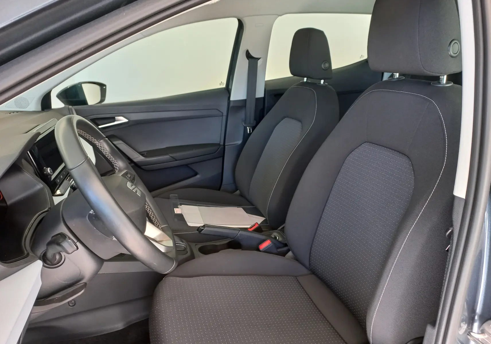 Vue intérieure côté conducteur de la SEAT IBIZA 2025 gris magnétique, montrant les sièges avant et le volant.