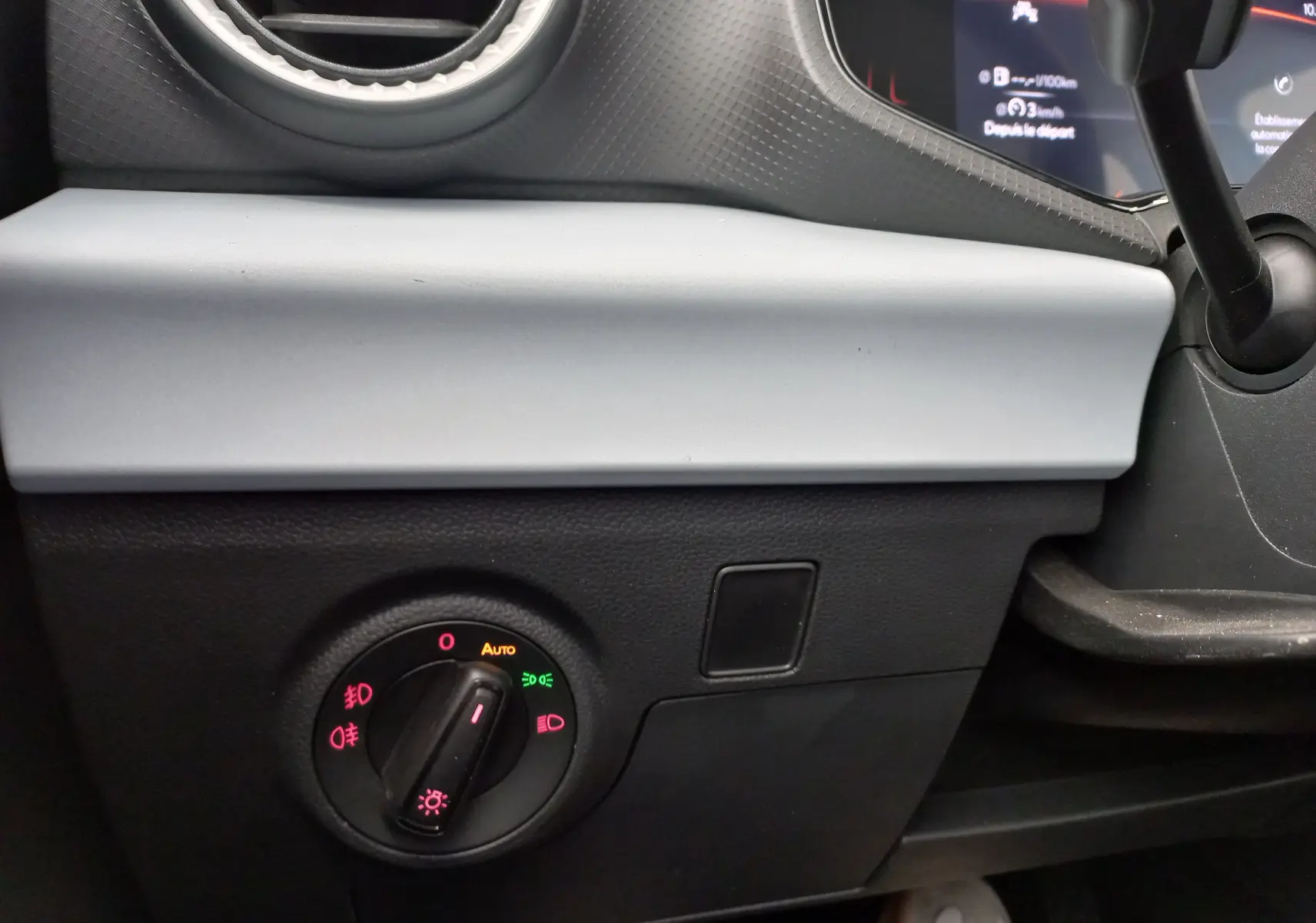 Détail intérieur du tableau de bord côté gauche d’une SEAT IBIZA gris magnétique 2025 avec commande des phares et aérateur rond.