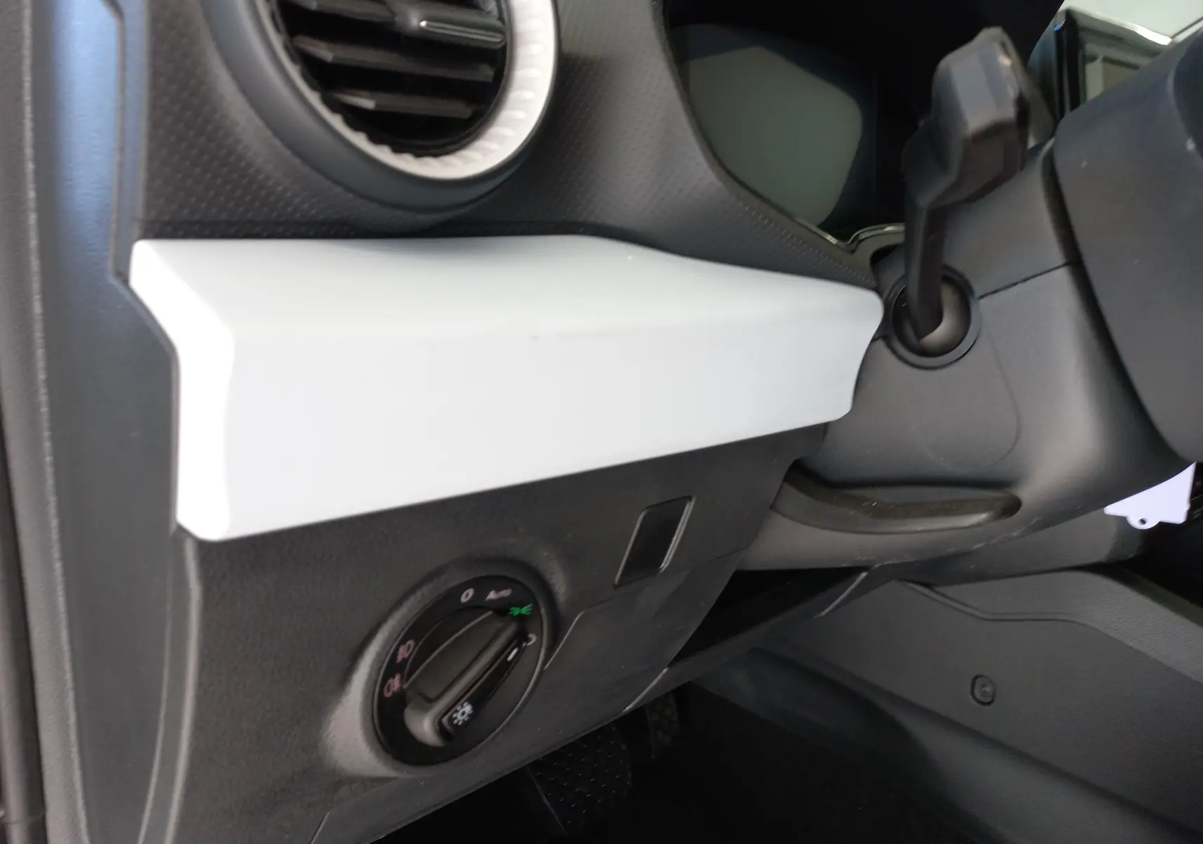 Détail intérieur côté gauche du tableau de bord de la SEAT IBIZA 2025 gris magnétique, avec commande d’éclairage et sortie d’air ronde.